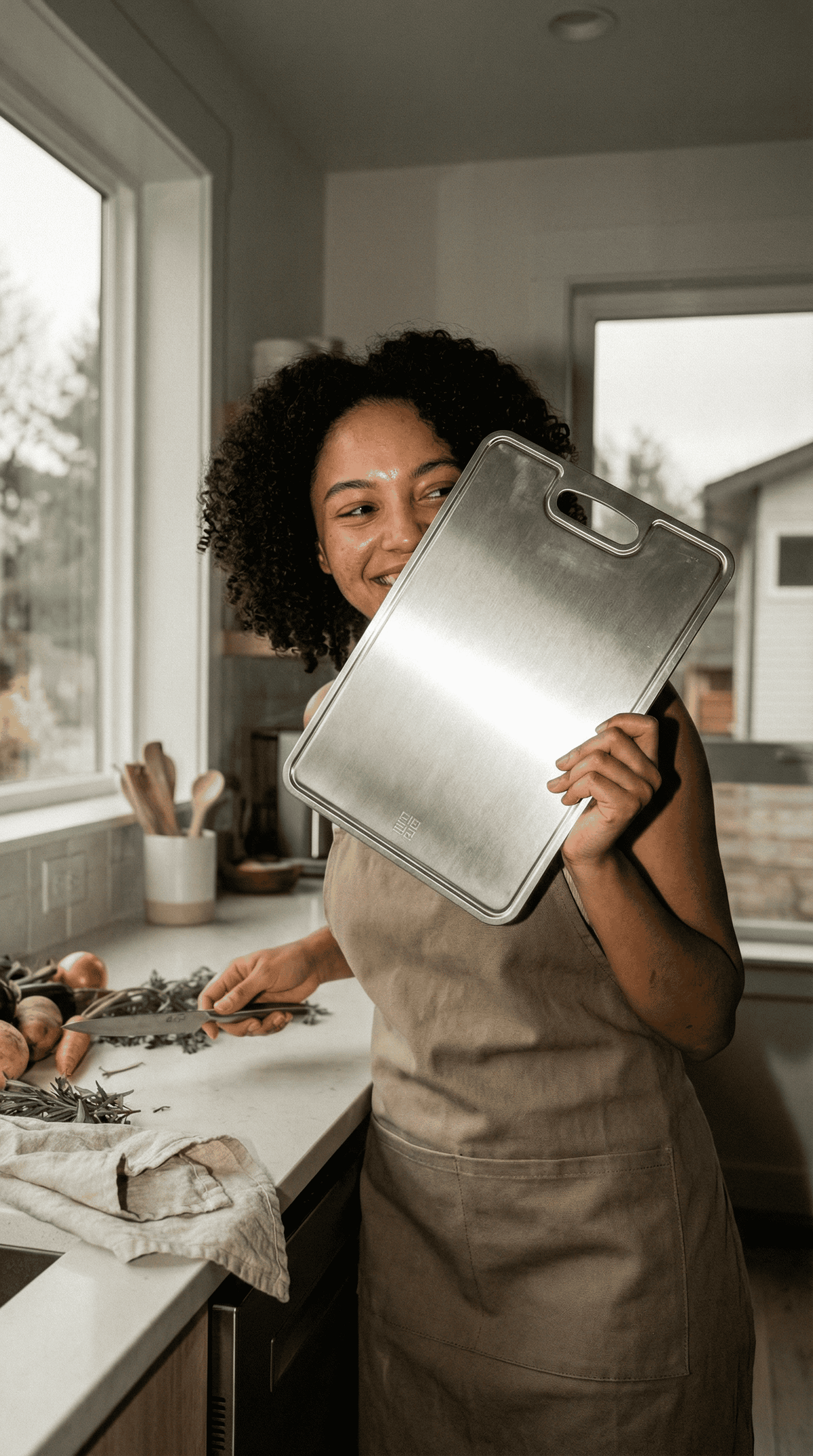 Smiling woman holding up a Siraat titanium cutting board, are titanium boards good for home kitchens
