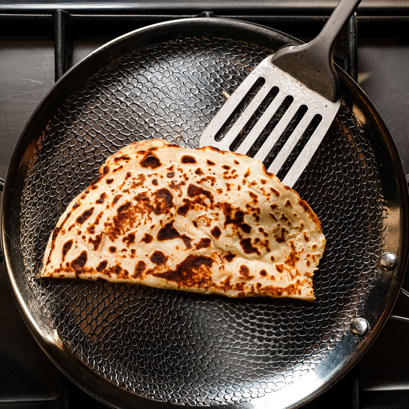 Flipping a crispy quesadilla with a Siraat titanium slotted turner in a hammered titanium pan