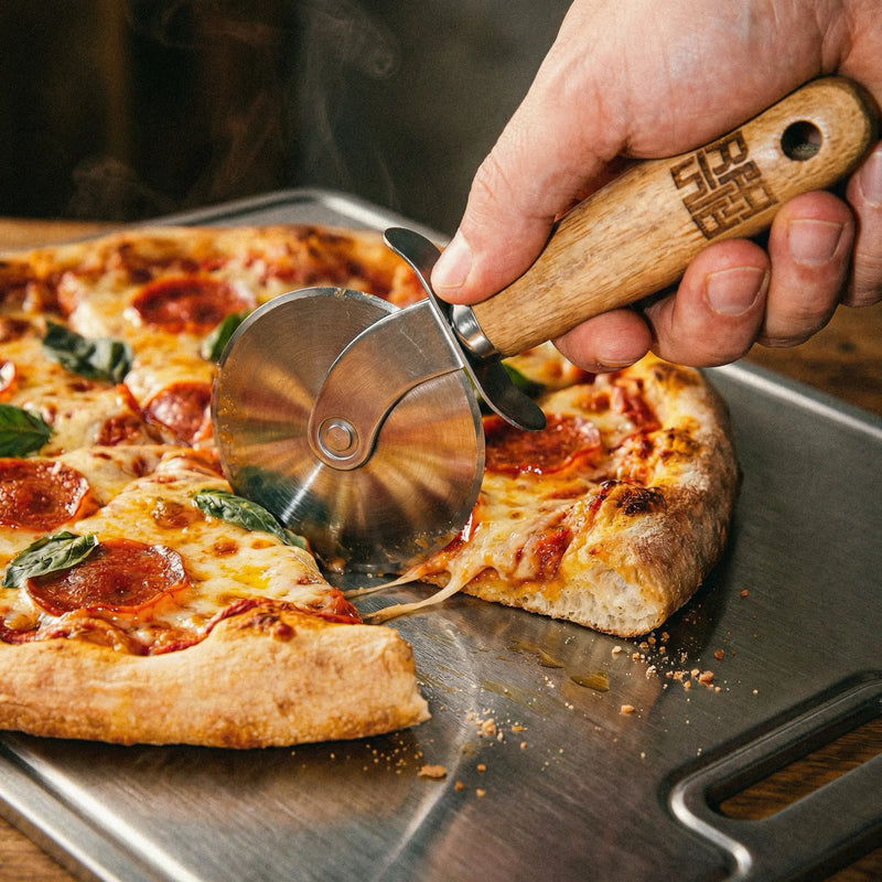 Cutting a pepperoni pizza with the Siraat Pizza Wheel, a steel blade with wooden logo handle