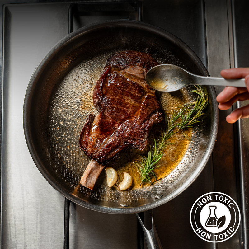 Ribeye basted in the Siraat Titanium Hammered Pan Pro With Lid, marked with a non-toxic badge