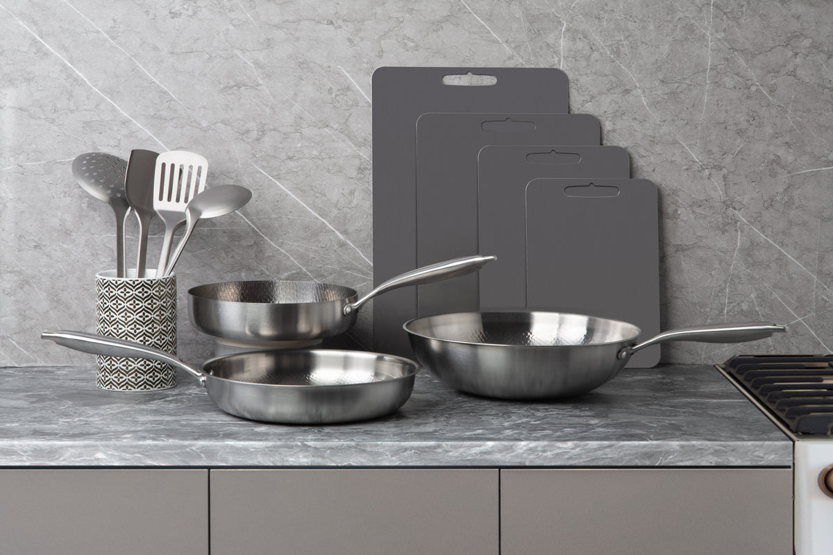Siraat titanium pans, cutting boards and utensils on marble, an elegant titanium cookware collection