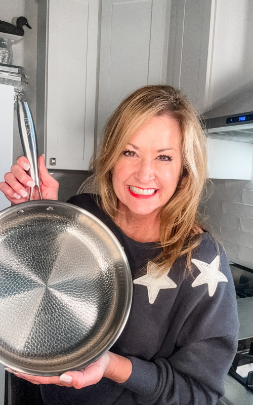 Smiling woman showing a Siraat titanium pan, why titanium nonstick cookware is a modern must-have