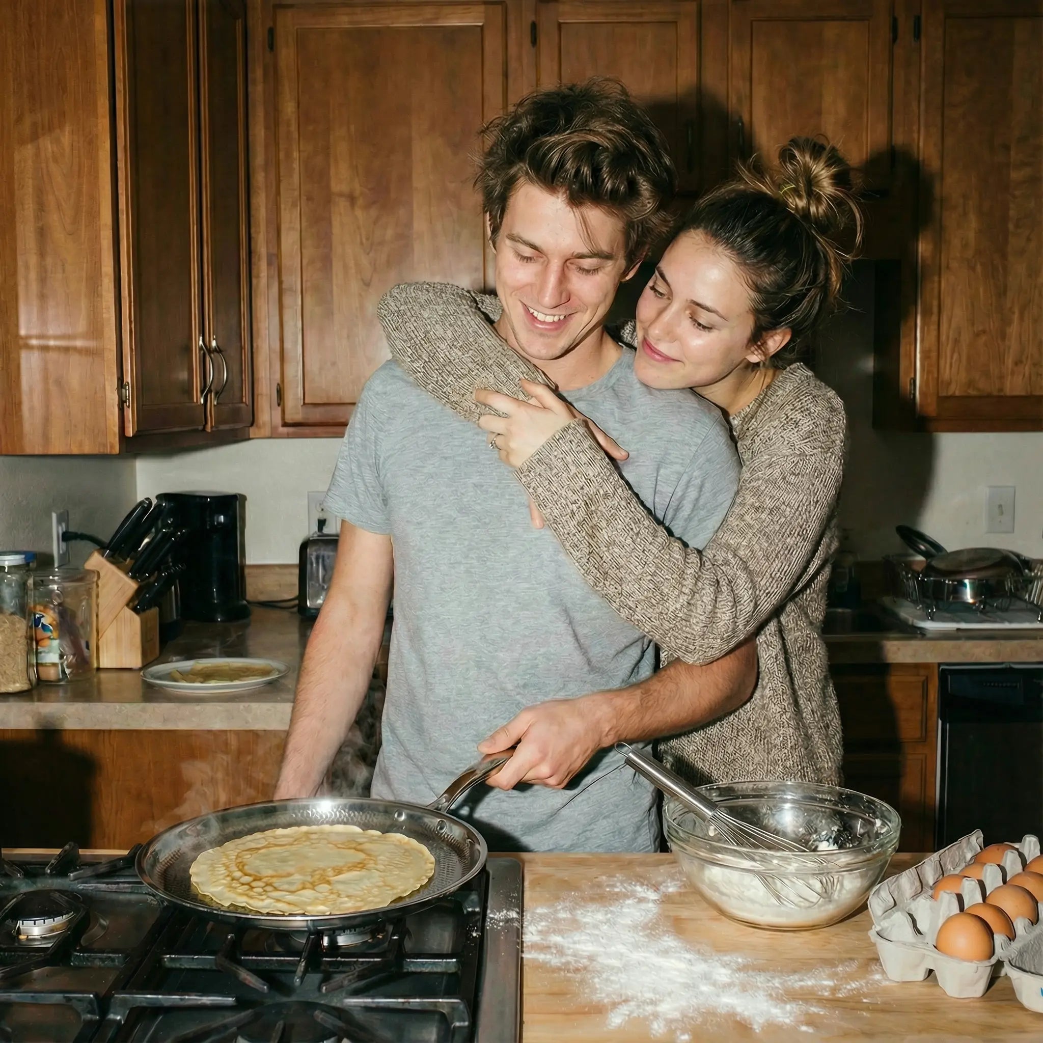 Couple hugging while making crêpes in the Siraat Titanium Hammered Crêpe Pan Pro at home